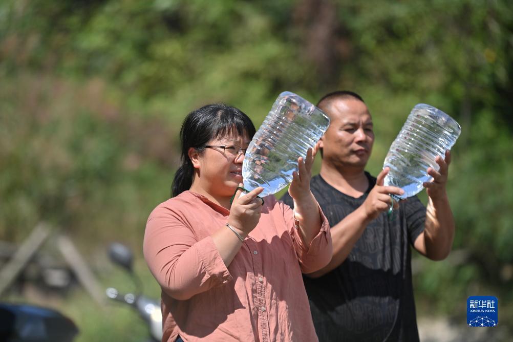 楊寧（左）在查看村民剛剛采集的水樣，為山泉水引水工程做準(zhǔn)備（10月8日攝）。新華社記者 黃孝邦 攝